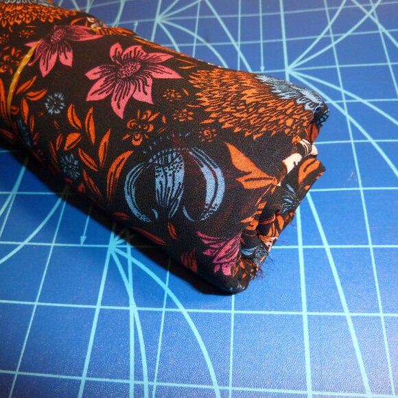 Fabric with blue, orange, red, and pink floral pattern on a black background - Picture 2 of 3